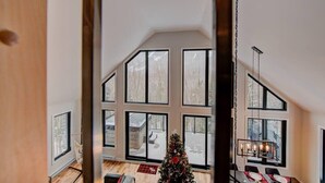 A spacious room with large windows, a dining area with a table and chairs, and a Christmas tree.