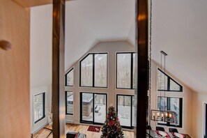 A spacious room with large windows, a dining area with a table and chairs, and a Christmas tree.