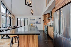 Une cuisine moderne dotée d’un grand îlot central, d’appareils électroménagers en acier inoxydable et de meubles de rangement en bois.