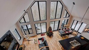 A spacious living area with a fireplace, a dining table, and a Christmas tree.