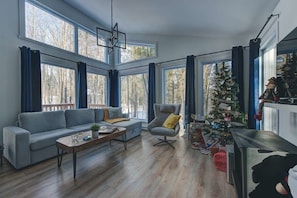 A modern living room with a sofa, armchair, coffee table, and a Christmas tree. - Le Baikal | Nature, Trails & EV Charger (Pont-Rouge)