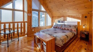 Een houten slaapkamer met een bed, een bureau en een bankje.