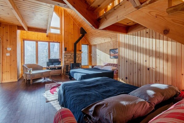 A cozy cabin with wooden walls, two beds, a TV, and a fireplace.