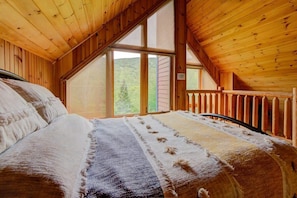 A wooden cabin bedroom with a bed, a window, and a view of the outdoors. - Boisé du Midi 66D | Nature at Massif du Sud (Saint-Philémon)