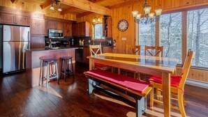 Ein Holzhütten-Interieur mit Küche, Essbereich und großen Fenstern.
