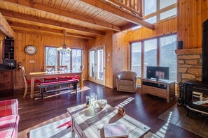 A wooden interior with a dining area, a television, and a fireplace. - Boisé du Midi 66D | Nature at Massif du Sud (Saint-Philémon)
