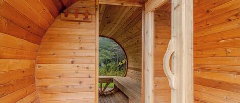 Una cabaña de madera con un tragaluz circular, un banco de madera y una puerta que da al exterior.