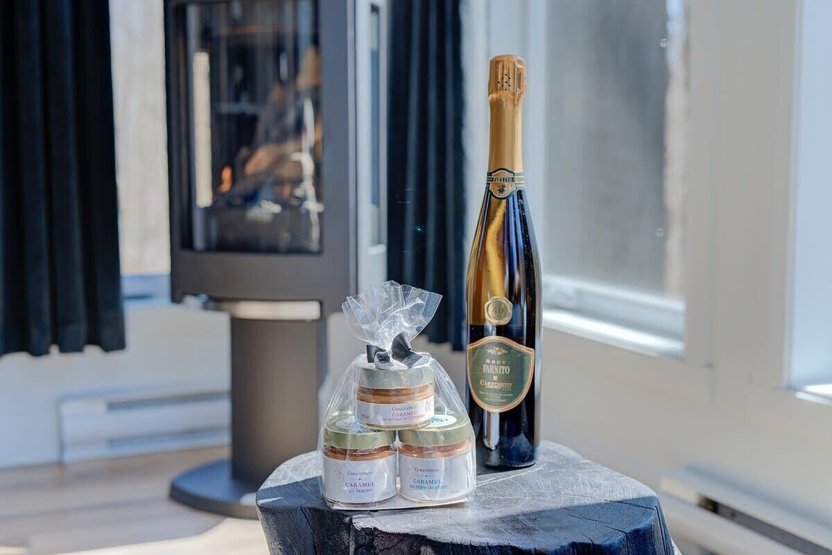 A bottle of Brut Farinito wine and two containers of Caramel body lotion on a wooden table.