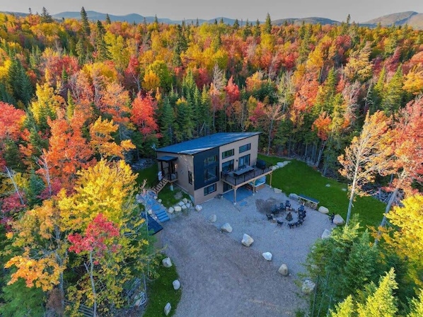 Una casa moderna de dos pisos rodeada por un bosque con follaje otoñal.