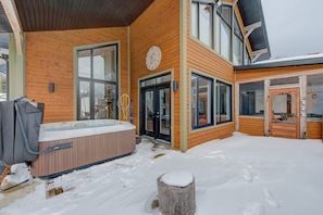 Eine Holzwand mit großen Fenstern, einem Whirlpool und einer Holzterrasse.