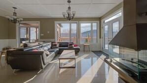 A modern living room with a sectional sofa, a glass coffee table, and a fireplace. - Pourquoi Pas! - Hot tub and Ski, Mountain view (Saint-Philémon)