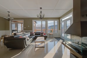 A modern living room with a sectional sofa, a glass coffee table, and a fireplace. - Pourquoi Pas! | Private Spa & Mountain View (Saint-Philémon)