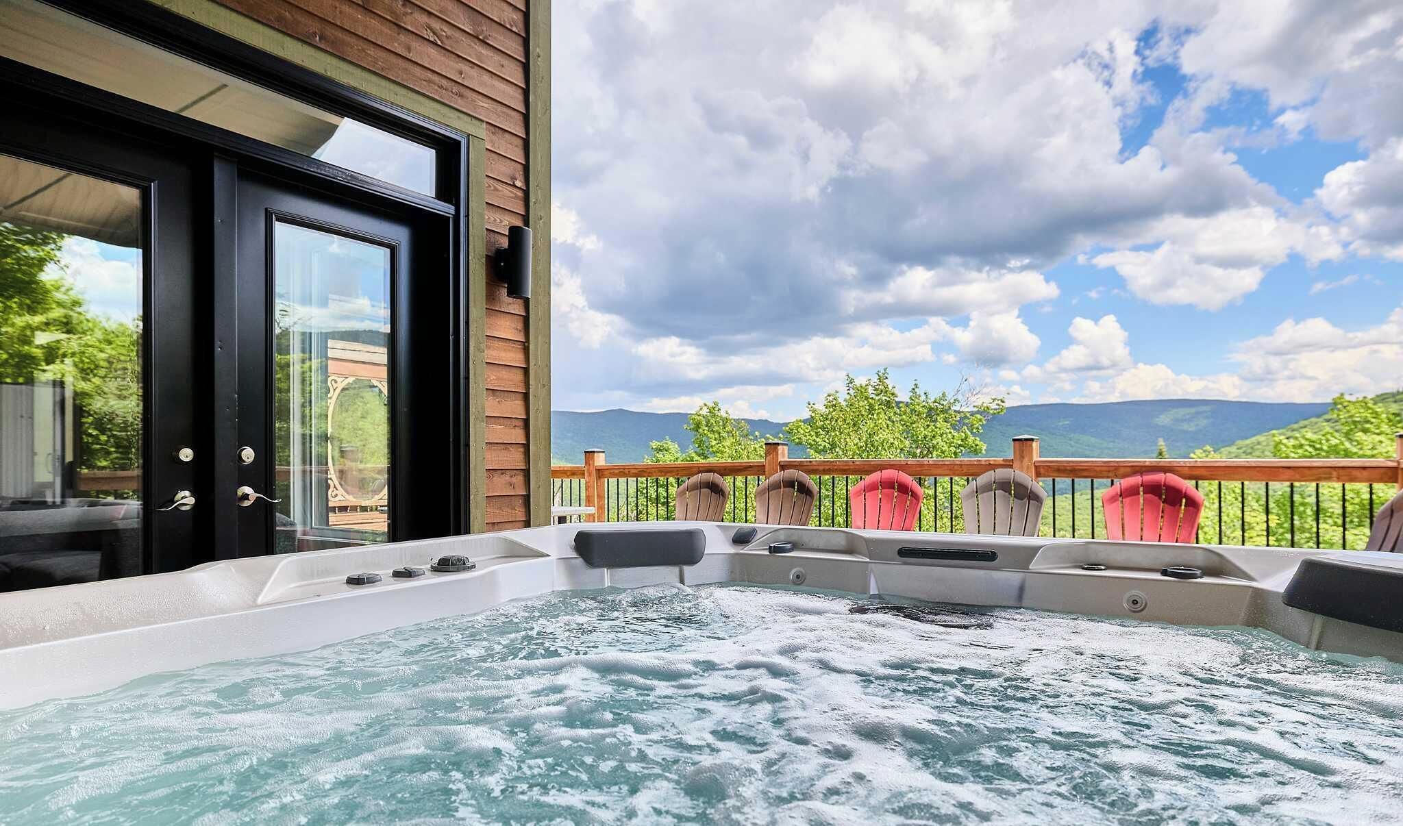 Un bain à remous sur un balcon, avec vue sur les montagnes et un ciel nuageux.
