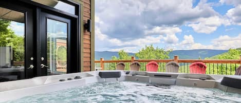 Un bain à remous sur un balcon, avec vue sur les montagnes et un ciel nuageux.