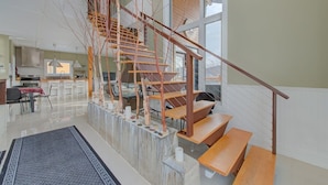 A modern interior with a wooden staircase, a kitchen area, and a dining space. - Pourquoi Pas! - Hot tub and Ski, Mountain view (Saint-Philémon)