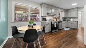 Une cuisine moderne avec des meubles gris, un îlot central et un coin repas avec deux chaises.