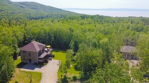A two-story house with a paved driveway and a small yard. - L'Escapade - Spa, billard & foyer (Petite-Rivière-Saint-François)