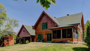 A large wooden house with a porch, a garage, and a well-maintained lawn. - Grandes-Piles | Spa, dock, navigable river & ski (Grandes-Piles)