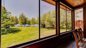 A room with large windows, wooden beams, and a view of a grassy area with trees and a body of water. - Grandes-Piles | Spa, dock, navigable river & ski (Grandes-Piles)