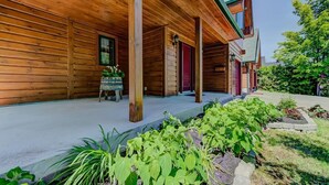 A wooden cabin with a porch, a small table with plants, and a garden area. - Grandes-Piles | Spa, dock, navigable river & ski (Grandes-Piles)