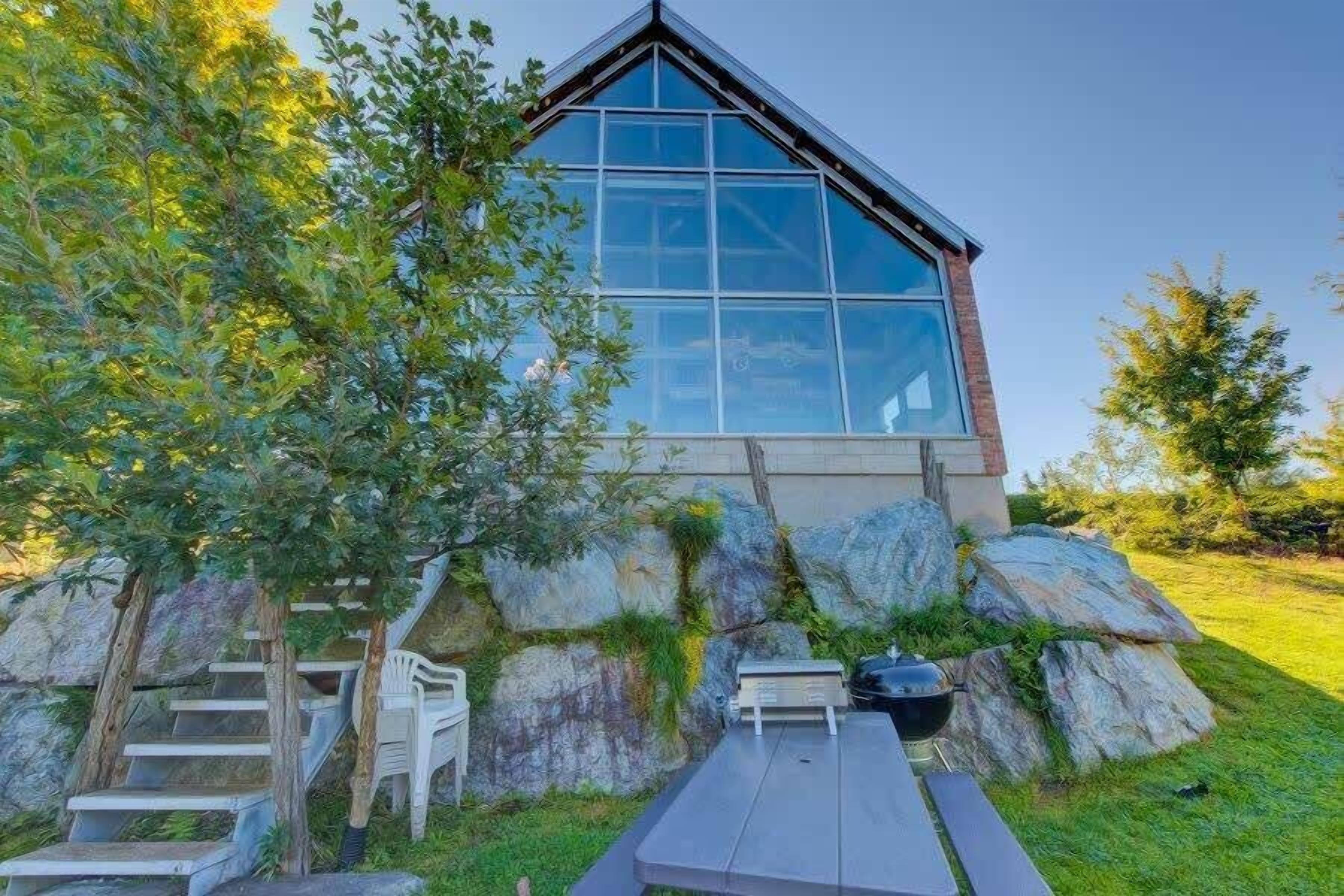 Un edificio moderno con amplios ventanales, fachada de piedra y una escalera de madera que conduce a la entrada.