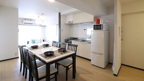 A compact kitchen with white cabinets, a white refrigerator, a microwave, and a dining table with chairs.