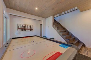 A room with a hockey table, a staircase, and a wall-mounted artwork.