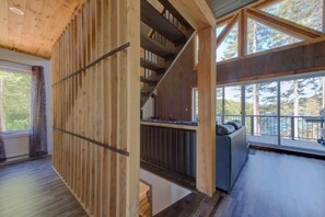 A wooden interior with a staircase, a balcony, and large windows.