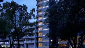 A multi-story building with balconies, surrounded by trees. - b hotel 102 Central Inner-Side Comfort Studio (Hiroshima City)