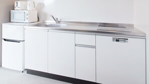 Une cuisine moderne avec des meubles blancs, une hotte en acier inoxydable, un four à micro-ondes et un grille-pain.