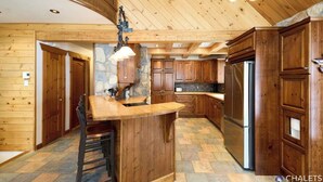 Una cocina amplia con armarios de madera, una isla central y una pared decorativa de piedra.