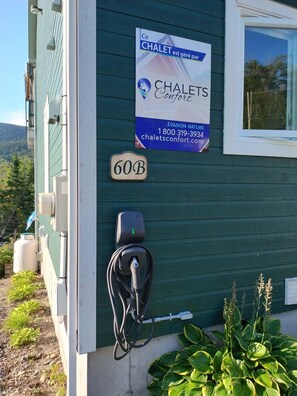 A house with a sign advertising 'CHALETS Confort' and a charging station for electric vehicles.