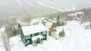 Un barrio residencial cubierto de nieve, con casas, cielo despejado y una montaña al fondo.