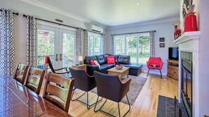 A spacious living area with a dining table, leather sofa, and a fireplace. - La Nouvelle-Angleterre - Hot tub and Dock (Pohénégamook)