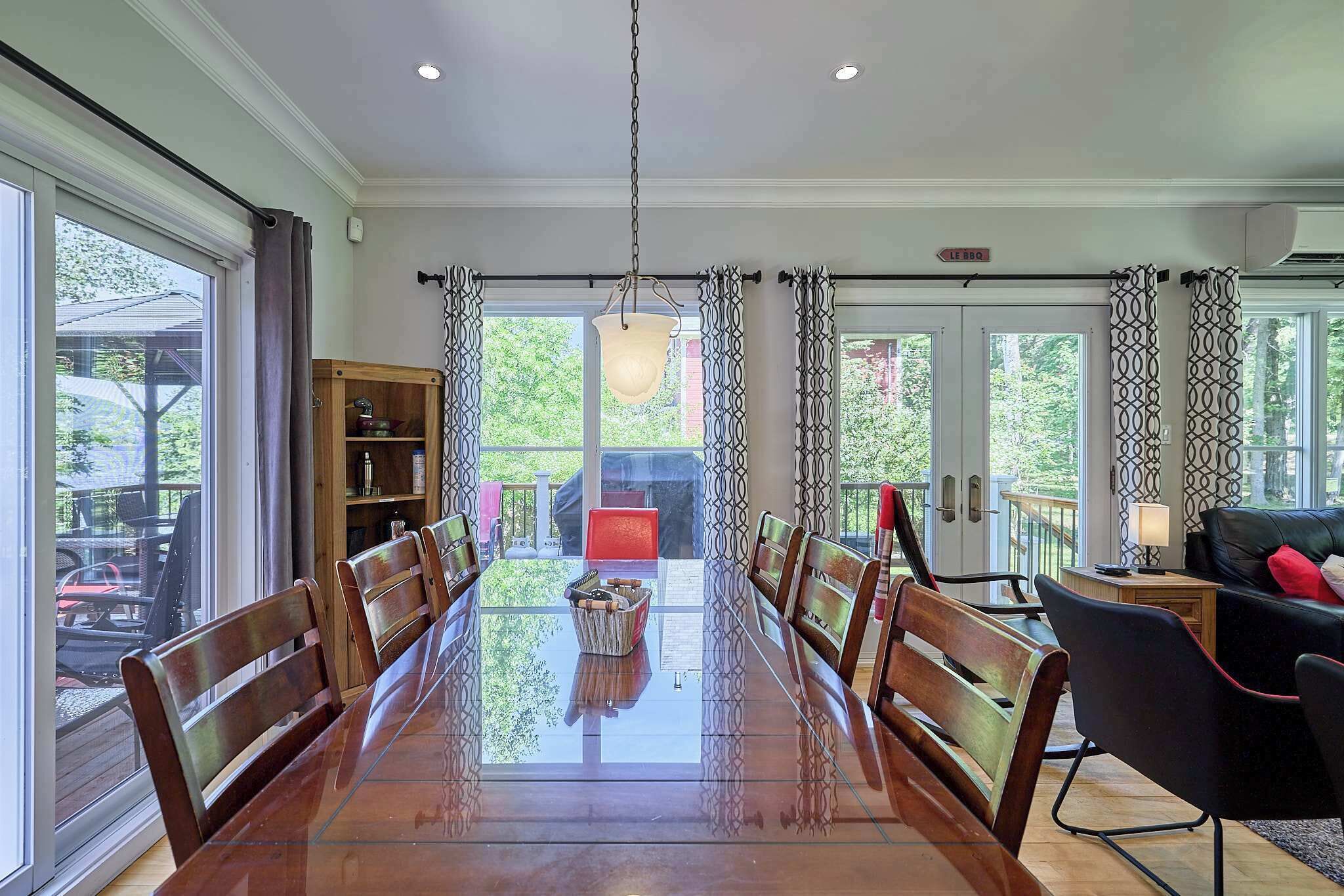 A dining area with a long table, chairs, and a hanging light fixture.