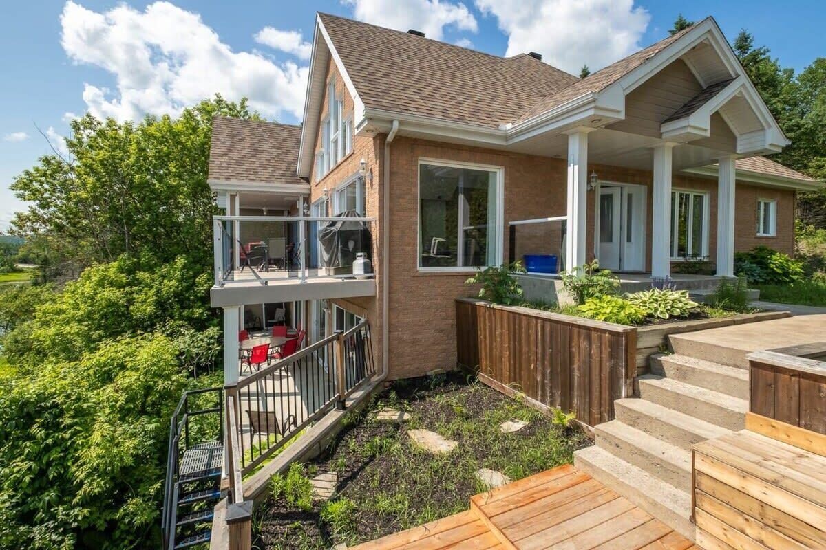 A two-story house with a balcony, a deck, and a backyard with a fire pit.