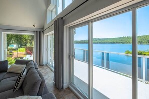 Un soggiorno moderno con un'ampia porta a vetri scorrevoli che si apre su un balcone con vista su un lago.