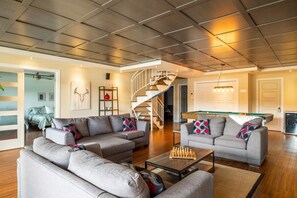 Ein modernes Wohnzimmer mit grauen Sofas, einem Holztisch und einer Treppe, die in eine andere Ebene führt.