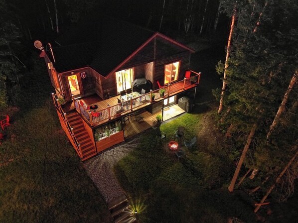 A cabin with a deck, a fire pit, and a satellite dish.