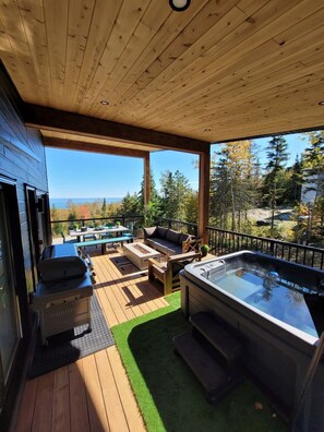 A deck with outdoor furniture, a hot tub, and a grill.