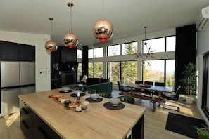A modern kitchen with a large island, stainless steel appliances, and large windows.