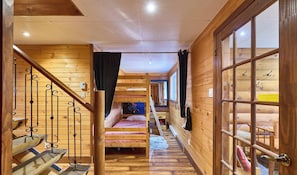 Un interior de madera con una litera, una escalera y una puerta de vidrio.