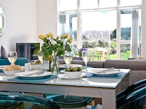 A dining table set with plates, glasses, and a vase of flowers.