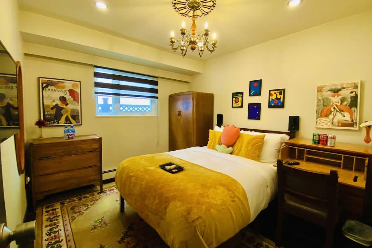 Una habitación de hotel con cama, cómoda, armario, escritorio y candelabro.