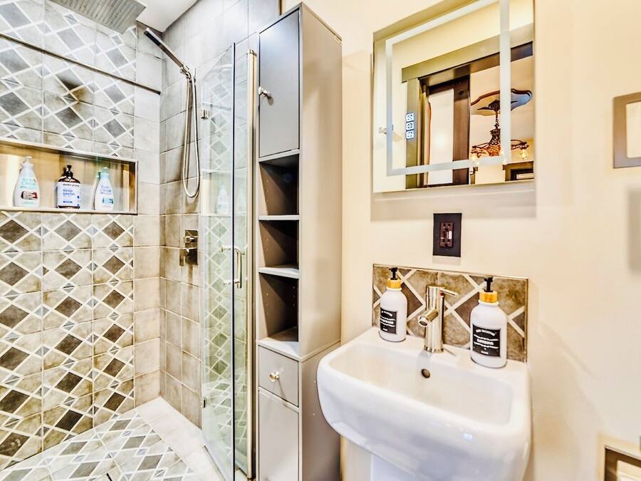 A bathroom with a shower, a sink, and shelves with toiletries.