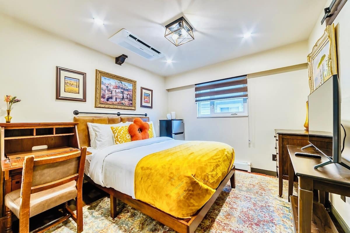 Habitación de hotel con cama, escritorio, silla, televisión y ventana.