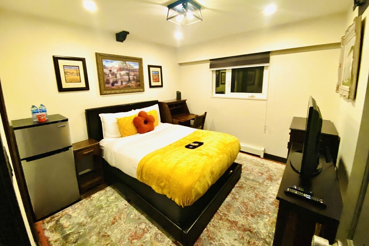 Una habitación de hotel con cama, escritorio, televisor y ventana.