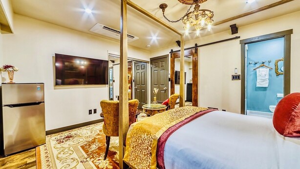 Una habitación de hotel con cama, televisión, minibar, zona de estar y baño.