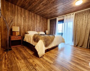 A bedroom with a wooden ceiling, a bed with a fur throw, a nightstand, and a lamp. - Amazing location with beautiful views (Pigeon Forge)