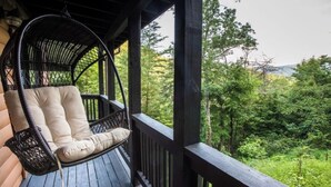 Une terrasse en bois avec un fauteuil suspendu en osier et un banc rembourré.